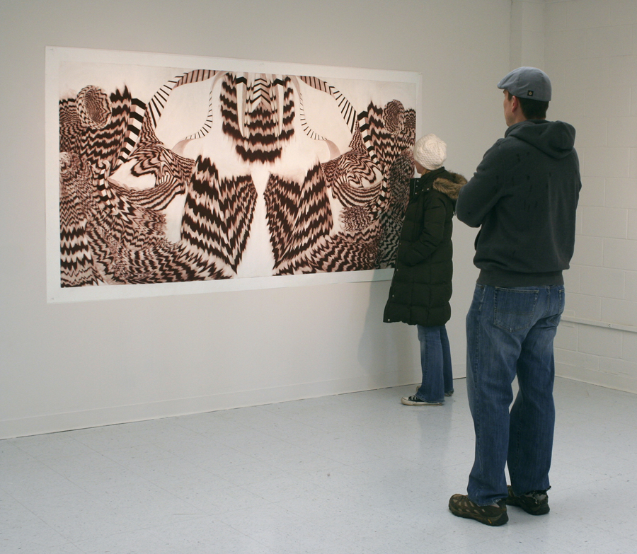 Warm brown and white striped and geometric drawing being encountered by two people in the gallery.